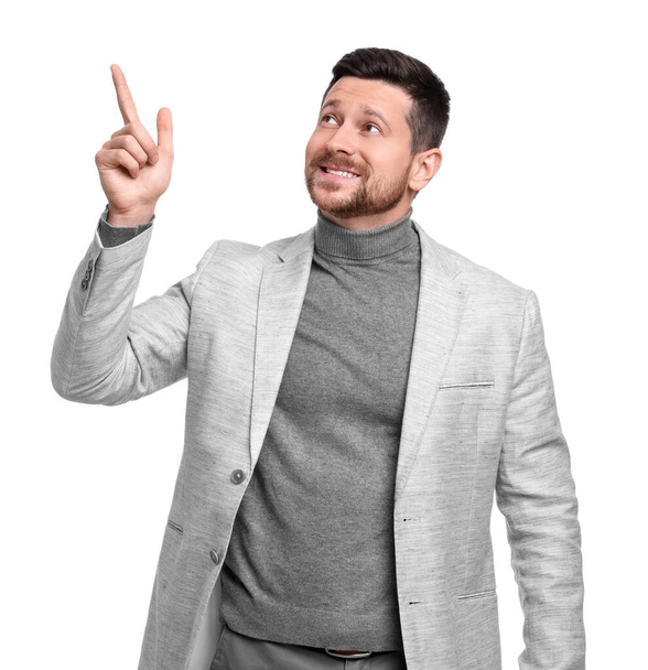 Handsome bearded businessman in suit pointing at something on white background - Foto, immagini