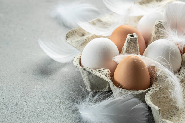 raw brown eggs and white eggs with chicken feathers, Concept of agriculture, bio and eco farming, bio food products. place for text, - Foto, Imagem