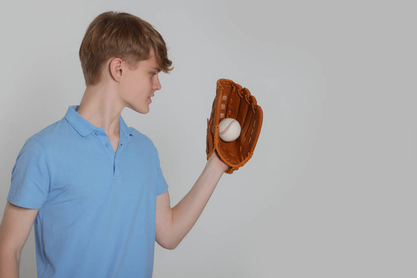 Teenage boy with baseball ball on light grey background. Space for text - Фото, изображение