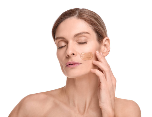 Woman with swatch of foundation on face against white background - Fotoğraf, Görsel