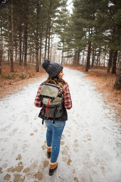 A túrázás nem menekülés, hanem realizmus. Hátulnézeti felvétel egy fiatal nőről, aki a vadonban túrázik télen. - Fotó, kép
