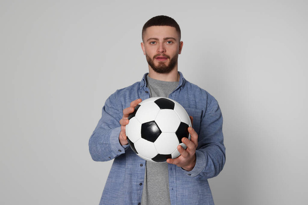 Athletic young man with soccer ball on light grey background, selective focus - Φωτογραφία, εικόνα
