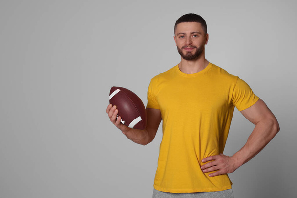 Athletic young man with American football ball on light grey background. Space for text - Photo, Image