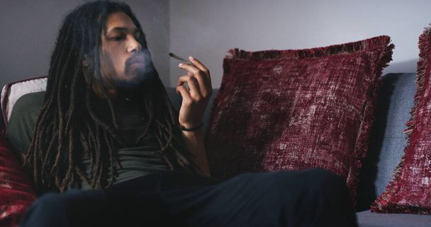 Getting high at home. a young man smoking a marijuana joint at home - Foto, imagen