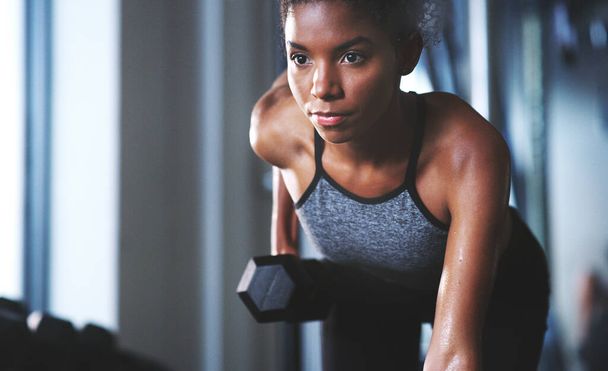 No cambiarás a menos que hagas un cambio. una joven deportista haciendo ejercicio con una mancuerna en el gimnasio - Foto, imagen