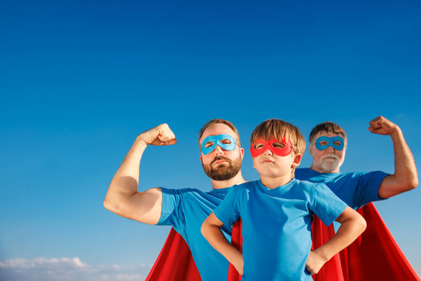 Senior, man and child outdoor against summer blue sky. Grandfather, father and son pretend to be superheroes. People having fun together. Family vacation and holiday concept. Happy Father's day - Zdjęcie, obraz
