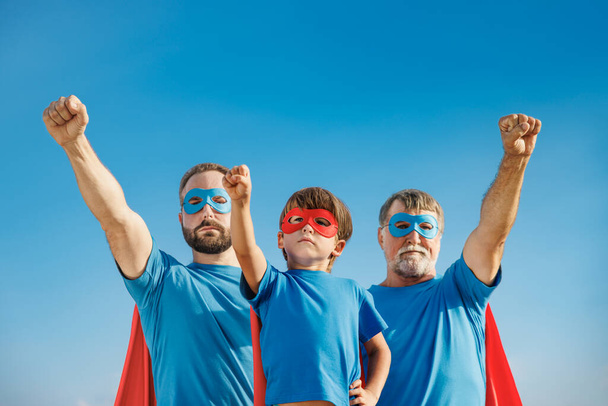 Senior, man and child outdoor against summer blue sky. Grandfather, father and son pretend to be superheroes. People having fun together. Family vacation and holiday concept. Happy Father's day - Photo, image