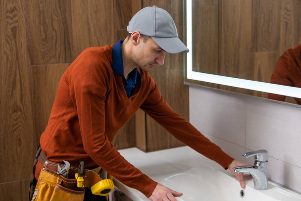 Homme installant robinet d'eau avec pomme de douche dans la salle de bain. - Photo, image