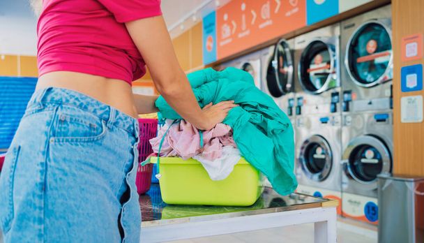 Young beautiful woman washes and dries clothes in the laundry. - Foto, Bild