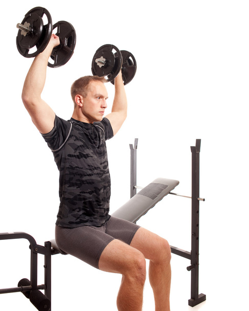 Young man lifting weights. Studio shot over white. - Фото, зображення