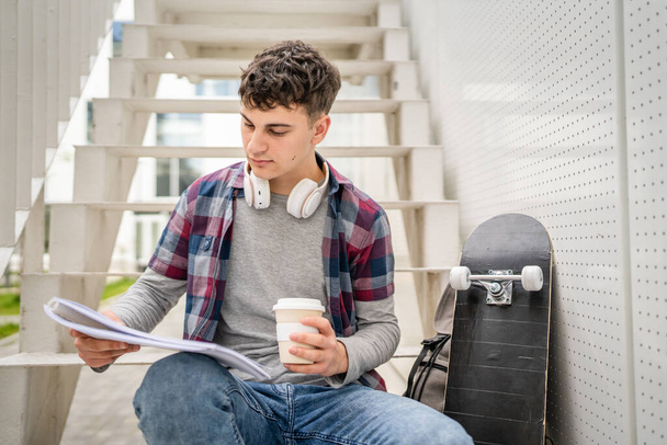 One Young man teenager caucasian student with books read study at campus in day sit on staircase education concept copy space - Φωτογραφία, εικόνα