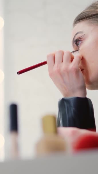 Filmik w zwolnionym tempie z niskim kątem kobiety nakładającej makijaż na linię wzroku za kulisami - Materiał filmowy, wideo