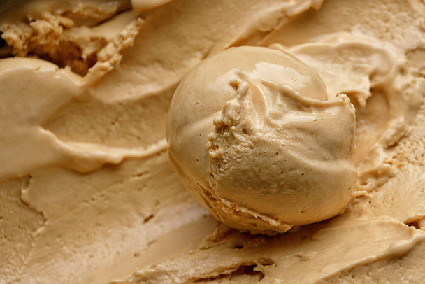 A scoop of peach ice cream close-up on a background of peach ice cream - Foto, Imagem
