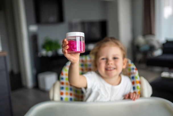 Kleines Mädchen spielt mit einem hausgemachten rosa Schleim. Kinder spielen zu Hause Schleimspielzeug. Hochwertiges Foto - Foto, Bild
