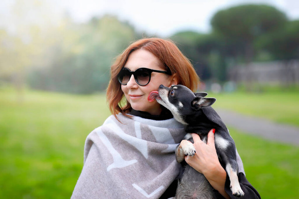 Middle-aged woman with her cute Chihuahua at the park. Adorable pet - Photo, Image