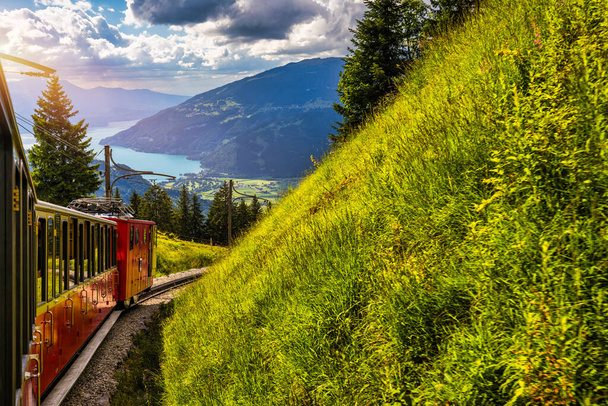 Červený turistický vlak, který jezdí z Wilderswil, v blízkosti Interlaken na slavné divoké květinové zahrady Schynige Platte, Švýcarsko. Retro vlak jede ze Schynige Platte do Interlakenu. Švýcarsko. - Fotografie, Obrázek