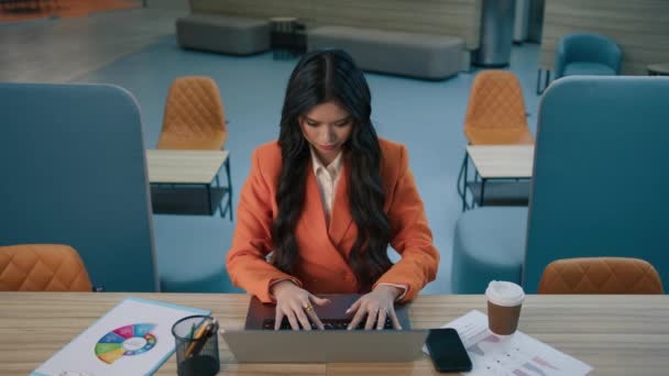 Konzentrierte asiatische Managerin der 20er Jahre sitzt am Schreibtisch und tippt auf dem Laptop im modernen Loft-Büro, lehnt sich im Stuhl zurück und streckt müde die Hände hinter den Kopf. - Filmmaterial, Video