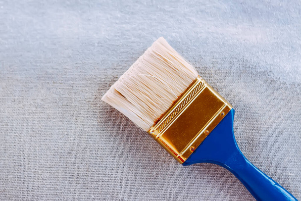 Synthetic paint brush and primer on canvas surface. - Valokuva, kuva