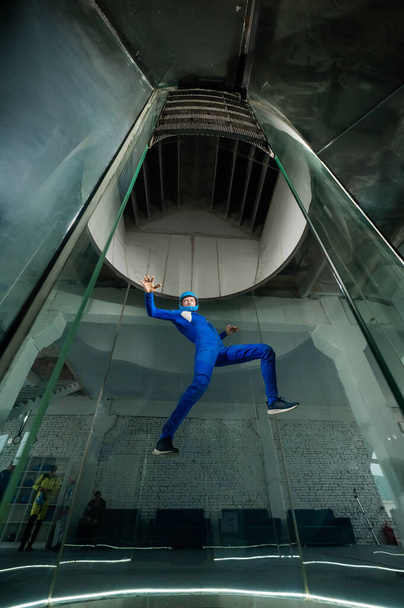 A man in overalls and a protective helmet enjoys flying in a wind tunnel. Free fall simulator. - Foto, Imagem