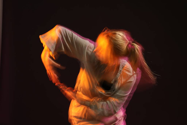 Young woman performing contemporary dance on black background, motion blur effect - Foto, afbeelding