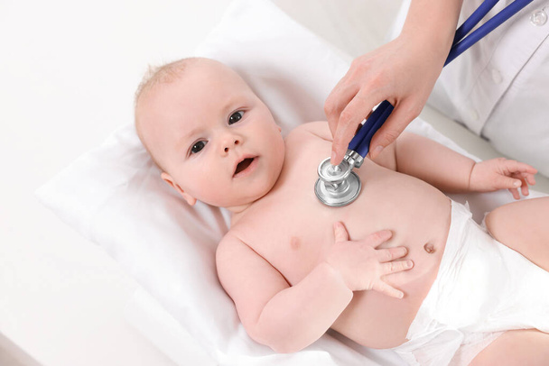Pediatrician examining cute little baby with stethoscope in clinic, above view - Photo, Image