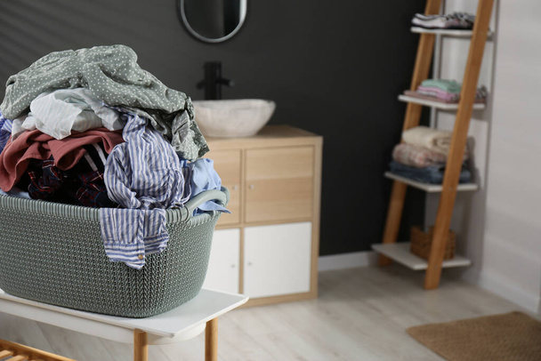 Laundry basket filled with clothes on table in bathroom. Space for text - Fotoğraf, Görsel