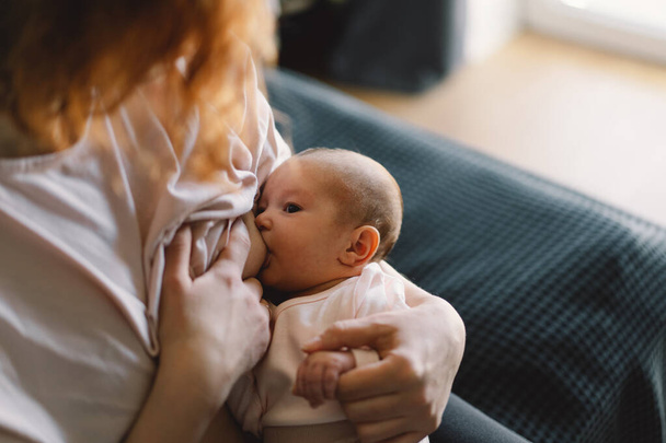 Newborn baby girl sucking milk from mothers breast. Portrait of mom and breastfeeding baby. Concept of healthy and natural baby breastfeeding nutrition. - 写真・画像