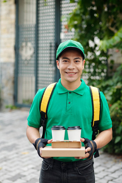 Πορτρέτο του χαμογελαστού διανομέα μεταφέρουν τα τρόφιμα για τον πελάτη - Φωτογραφία, εικόνα