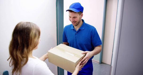 Happy Young Woman Accepting Parcel Box From Delivery Man - Фото, изображение