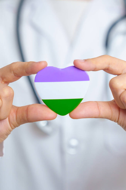 Queer Pride Day and LGBT pride month concept. Doctor hand holding purple, white and green heart shape with Stethoscope for Lesbian, Gay, Bisexual, Transgender, genderqueer and Pansexual community - Фото, зображення