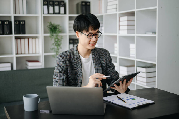 Young business man executive manager looking at tablet pc watching online webinar training or having virtual meeting video conference doing market research working in modern office - 写真・画像