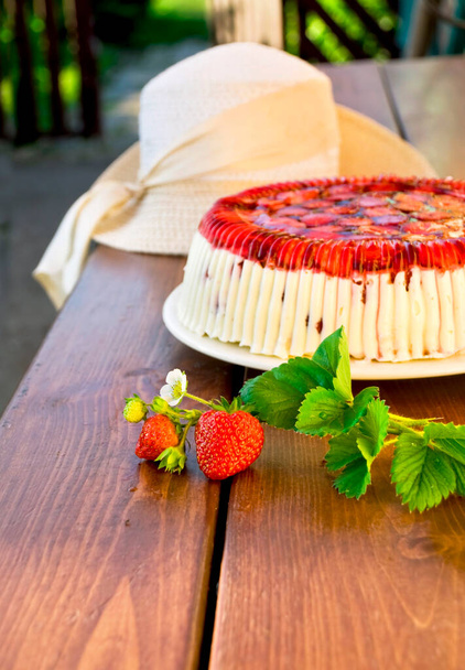 Cake with strawberries and whipped cream decorated with leaves on wooden background - Φωτογραφία, εικόνα
