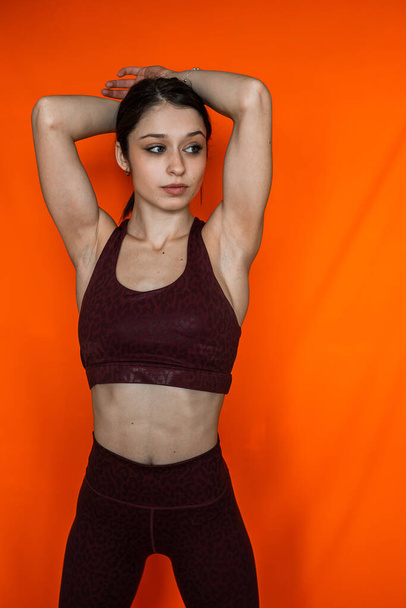 Портрет стройная женщина носить спортивную ткань изолированы на оранжевом фоне. Здоровый образ жизни - Фото, изображение