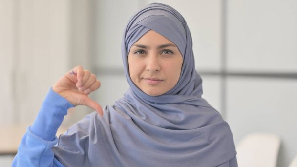 Retrato de una mujer musulmana en Hijab haciendo pulgares hacia abajo - Foto, Imagen