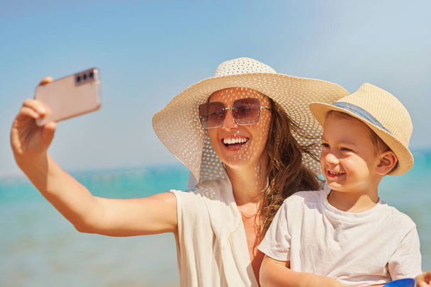 Obraz matki z synem robiącej selfie na plaży. Wysokiej jakości zdjęcie - Zdjęcie, obraz