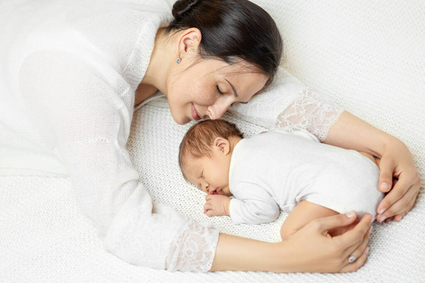 Smiling Mother sleep with Newborn on White Blanket. Dreaming Mom hugging Baby lying down on Stomach. Happy Motherhood and Parenting. Infant Health Care. Child Protection - Foto, imagen