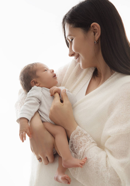 Mother with Newborn. Happy Mom hugging Baby. Happy Woman holding one Month little Child in Hands over White. Parent playing with Infant. Kids Health Care and Parenting - Фото, изображение