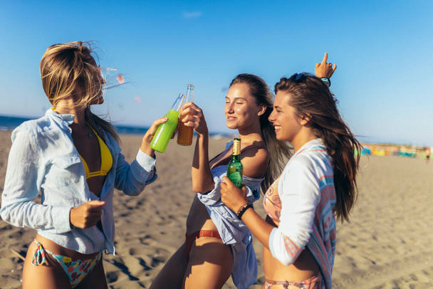 Kadın arkadaşlar güneşli bir günde kumsalda eğleniyorlar. - Fotoğraf, Görsel