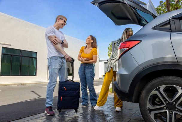 Caucasian family is fitting their luggage in the trunk after renting a car at the airport terminal for weekend vacation travel concept - Photo, Image