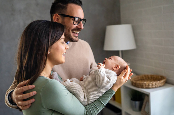 Peaceful young married couple enjoying being family, parents, holding new born baby in arms, standing close together. Parenthood, childbirth, relationship concept - Foto, Imagem