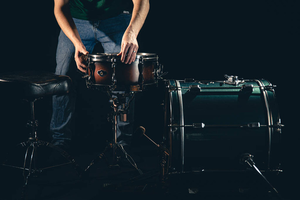Ein männlicher Schlagzeuger und ein Schlagzeug auf schwarzem Hintergrund, der Musiker bereitet sich darauf vor, zu spielen. - Foto, Bild
