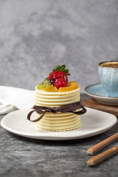 Κέικ φρούτων. Φράουλα, αχλάδι, ακτινίδιο και κέικ βατόμουρο καλύπτονται με λευκή σοκολάτα σε σκούρο φόντο. Γλυκά ζαχαροπλαστικής - Φωτογραφία, εικόνα