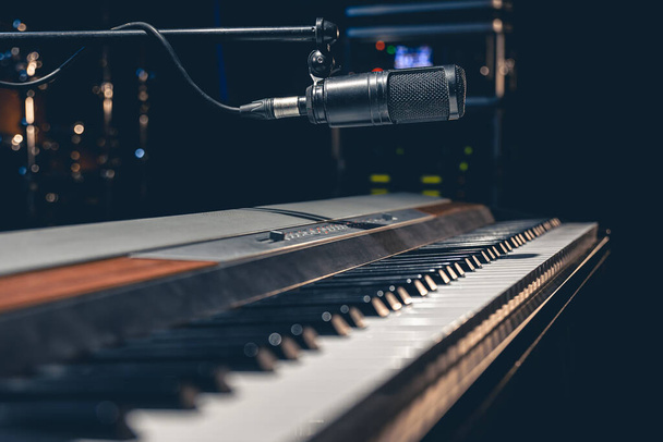 Teclas musicales y un micrófono sobre fondo oscuro, un piano electrónico en el escenario o en un estudio de música. - Foto, imagen