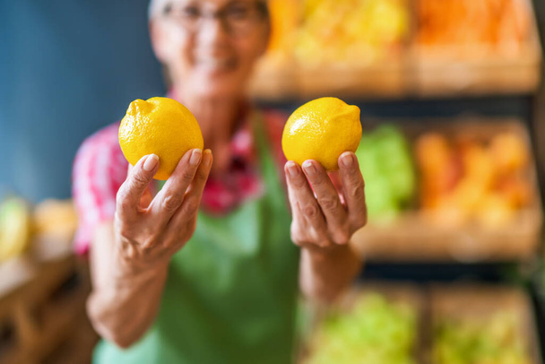 果物や野菜の店で働く人がレモンを持っています。レモンの終わり. - 写真・画像
