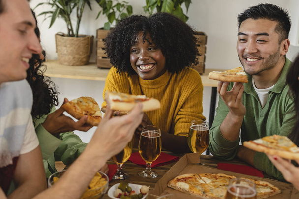 cheerful multiracial friends eating pizza at home - millennial friends enjoying weekend together - focus on african american woman - - Photo, Image