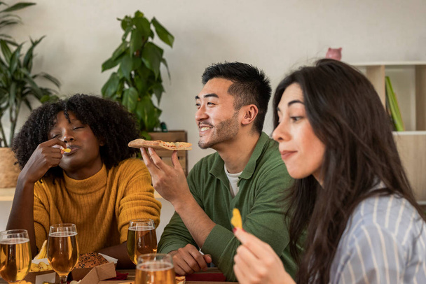Fröhliche Freunde, die zu Hause Pizza essen - Fröhliche Millennial-Freunde, die das Wochenende zusammen genießen - Lifestylekonzept für junge Leute - Foto, Bild