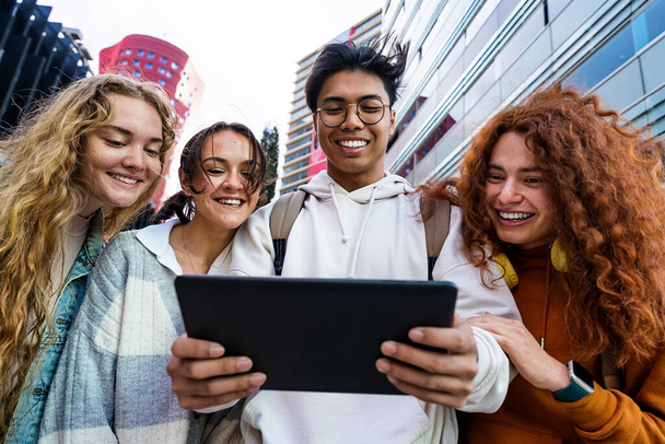 Şehirdeki bir grup genç öğrenci, çevrimiçi komik içeriği paylaşmak için dijital tablet kullanıyor - Fotoğraf, Görsel