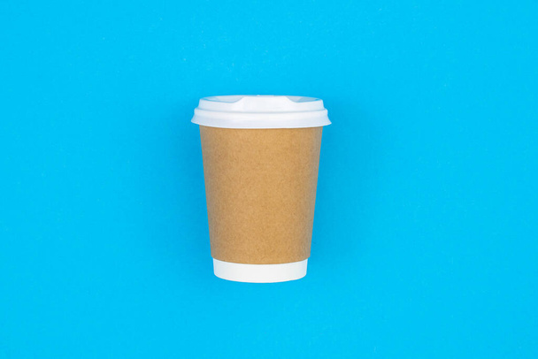 Disposable craft paper cup on a blue background, top view, copy space. - Fotó, kép