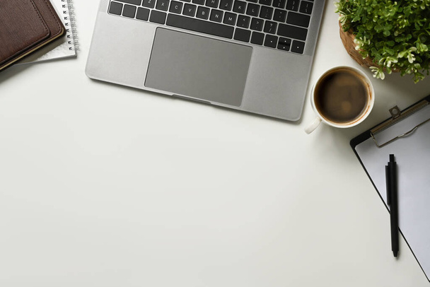 Tavolo da ufficio moderno bianco con computer portatile, tazza di caffè e notebook. Vista dall'alto con spazio di copia, disposizione piatta - Foto, immagini