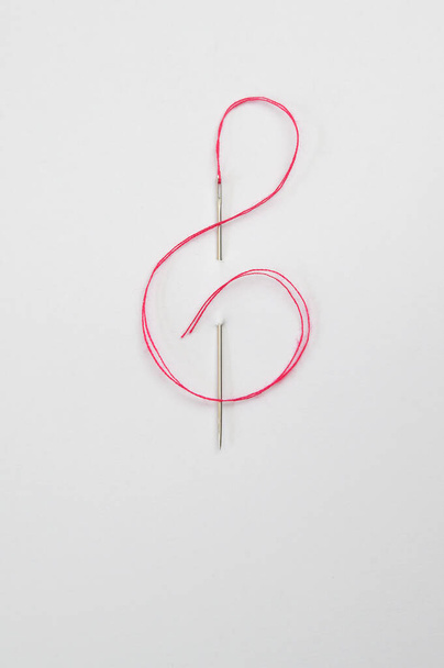 Rote Kordel durch das Nadelöhr in Form eines Notenschlüssels - Foto, Bild